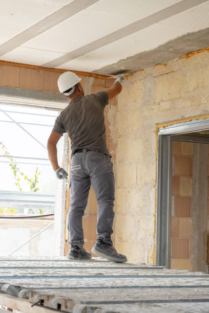 istock Craftsmen in grey clothes working inside a room standing on scaffoldings during construction 2187149421