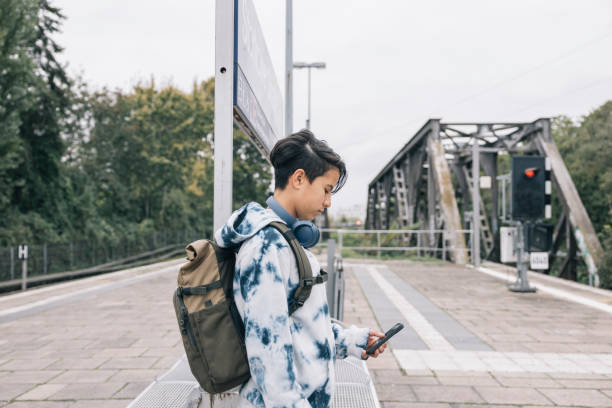 istock Teen student using smartphone while waiting for train at station 2187151658