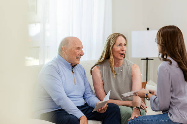 Unrecognizable mid adult daughter helps her parents with choosing a therapy center for her dad The senior adult couple listens to their daughter while she helps them pick a therapy center. father daughter 80s stock pictures, royalty-free photos & images