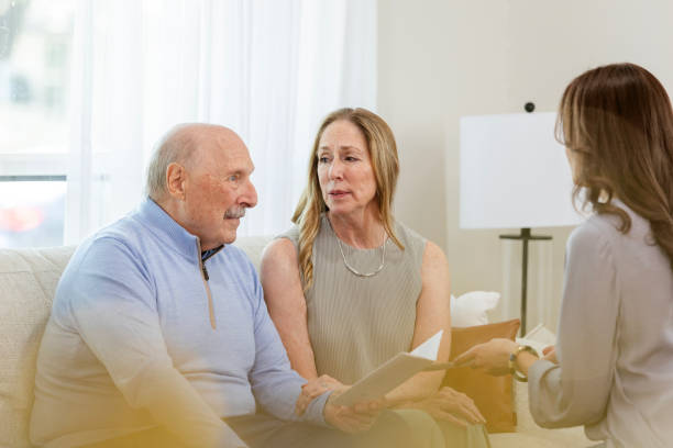 Senior adult male and his wife meet with the doctor to talk about his upcoming surgery The senior adult male sits in the doctor's office with his wife to talk about his upcoming surgery. father daughter 80s stock pictures, royalty-free photos & images