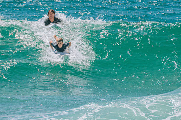 Australian boy learning surfing with father watching guidance in gold coast