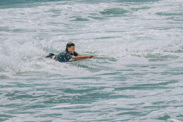 istock Australian boy surfing returning to beach with surfboard 2187163305