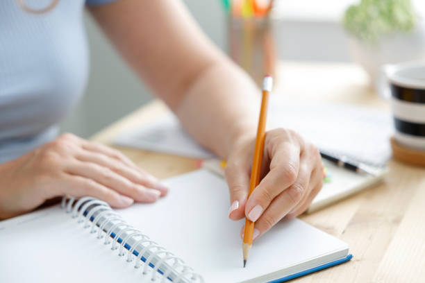 istock Woman taking notes in a diary with a yellow pencil 2187167726