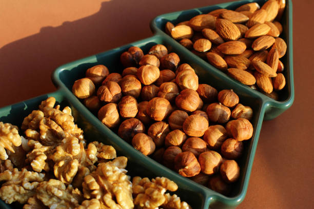 different types of nuts. Various snacks for the New Year table in a plate in the shape of a Christmas tree. walnut, hazelnut, almond