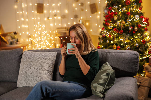 istock Woman enjoying a hot drink by the Christmas tree 2187171799