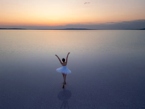 istock Ballerina dancing in a salt lake at sunset, performing a graceful pose 2187173566