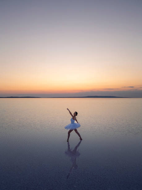 istock Ballerina dancing on water at sunset, performing a graceful pose 2187173574