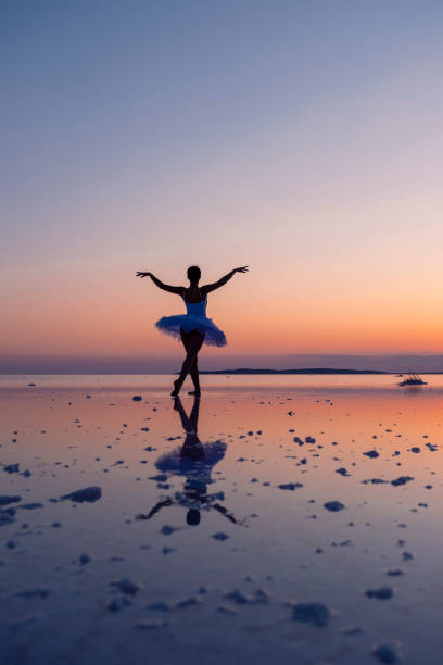 istock Ballerina dancing on the water at sunset with reflection 2187173742
