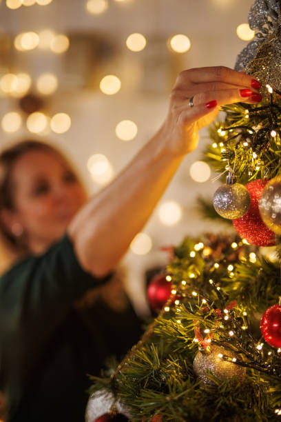 istock Cheerful woman decorating a Christmas tree in a cozy room 2187173902