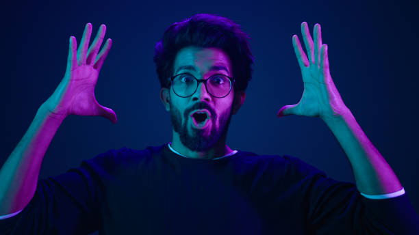 Male portrait neon ultraviolet background Arabian man Indian guy coder hacker showing head mind explosion gesture boom brainstorm idea mental shock information think computer technology sci-fi future