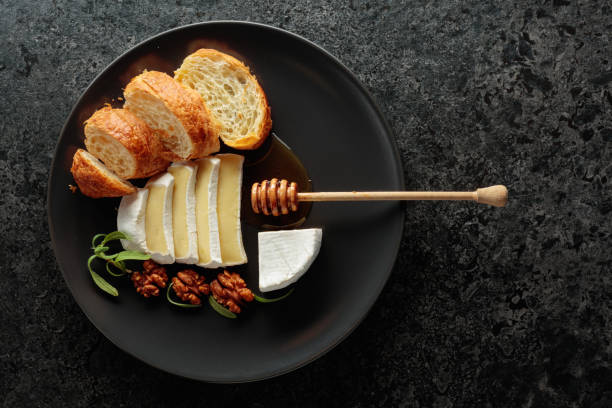 istock Camembert cream cheese with honey, croissants, and walnuts on a black plate. 2187175229
