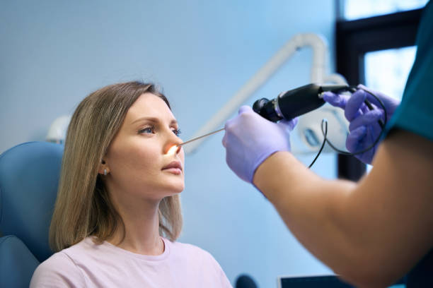 ENT doctor otolaryngologist with headlight treat nose woman patient stock photo