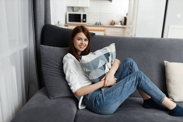 istock pretty woman with pillow in hands comfortable sofa 2187181233