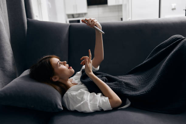 istock woman with mobile phone resting lying on the sofa indoors 2187182274