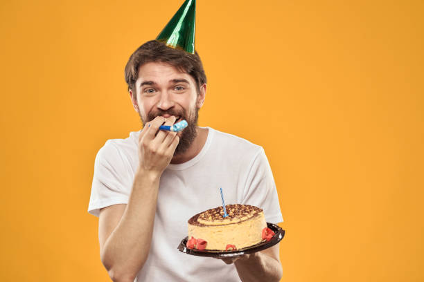 istock A bearded man with a cake and in a cap celebrating his birthday 2187182309