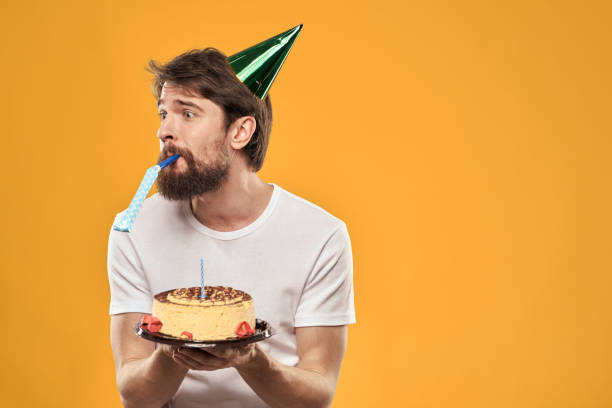 istock birthday boy in a cap with cake fun yellow background party 2187183931