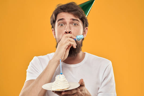 istock birthday boy in a cap with cake fun yellow background party 2187184341