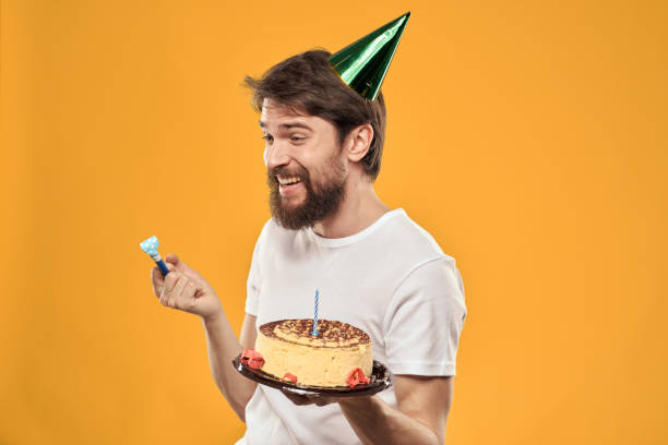 istock birthday boy in a cap with cake fun yellow background party 2187184344
