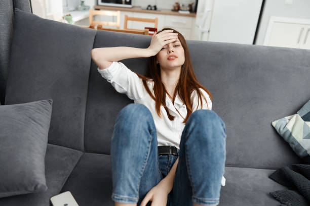 istock woman sitting on the couch feeling unwell hand on face stress 2187184483