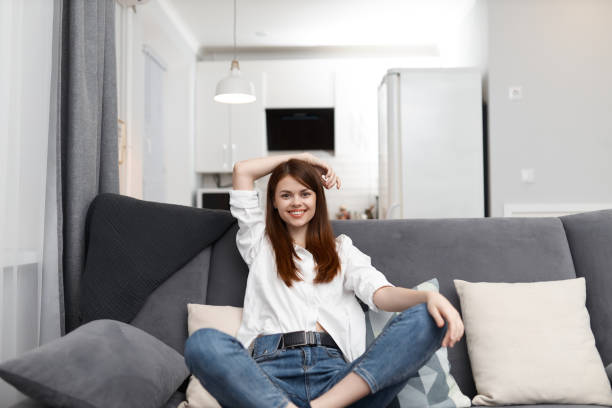 istock smiling woman sitting on the sofa with pillows comfortable apartment free time 2187184485
