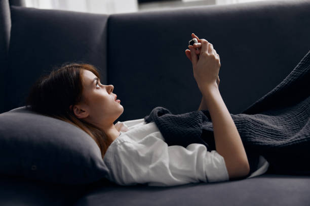 istock woman on a gray sofa with a mobile phone in her hand comfortable home 2187184565