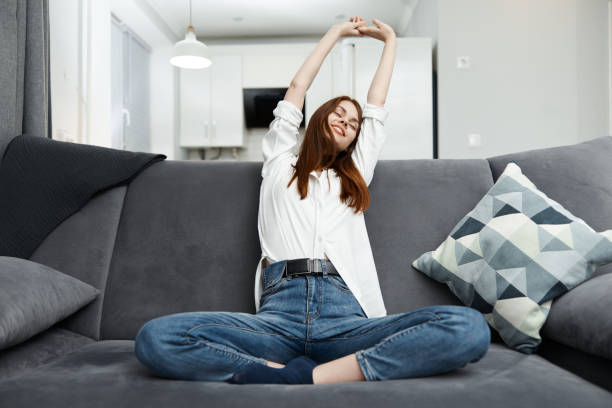 istock woman pulls herself up holding her hands above her head On the couch at home rest 2187185742