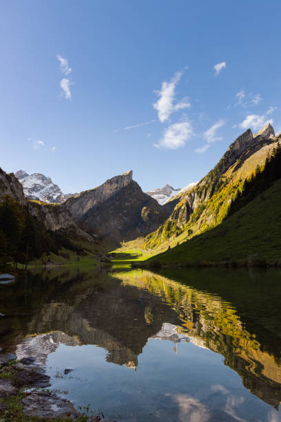 A mountain lake with crystal clear waters reflects the majestic peaks and sunny slopes of the Alps, creating a picturesque picture of peace and natural beauty. A boat on the shore adds an element of adventure, emphasizing themes of relaxation, ecotourism and harmony with nature.