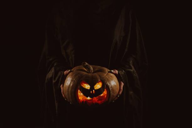 istock The witch is holding a pumpkin jack o lantern glowing in the dark. Halloween. 2187199374