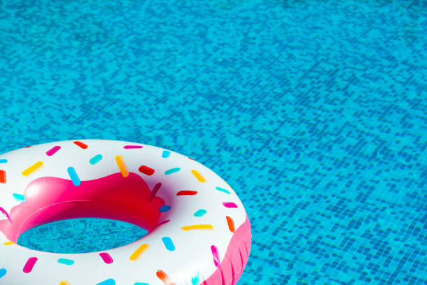 istock A pink plastic pool float shaped like a donut with sprinkles in a swimming pool with copy space 2187200627