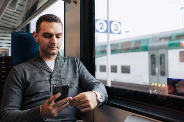 istock Young Man Using Smartphone While Traveling on Train for Business 2187200649