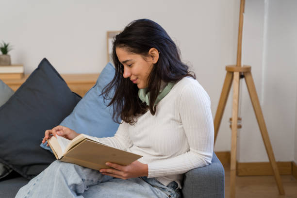 istock woman reading a book on the sofa at home 2187202319
