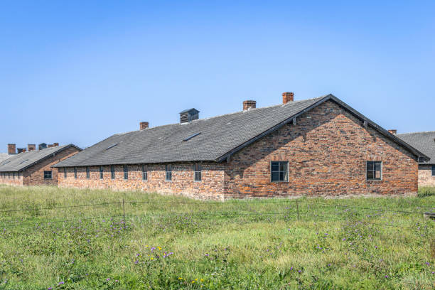 A haunting view of the barracks at Auschwitz II-Birkenau in Oswiecim, Poland, the largest of the Nazi concentration and extermination camps during the Holocaust. These barracks were overcrowded and lacked basic necessities, housing thousands of prisoners under inhumane conditions. Between 1942 and 1944, more than a million people, primarily Jews, were deported to Auschwitz-Birkenau, where many were forced into grueling labor or sent to their deaths in the camp’s gas chambers. This site is now a Holocaust memorial and museum, serving as a reminder of the atrocities committed during World War II.