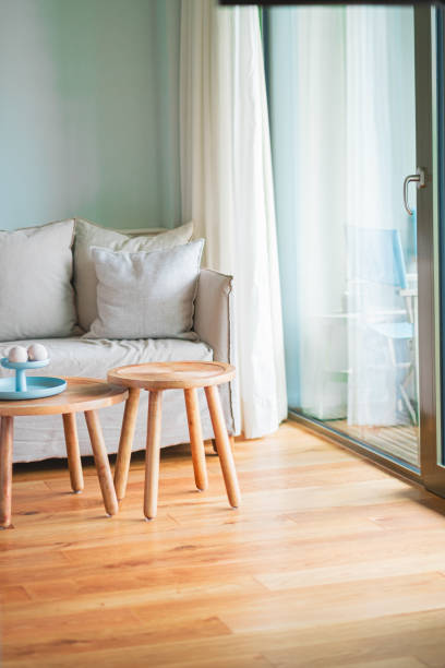istock Cozy Living Room Interior Featuring Wooden Coffee Tables, Comfortable Sofa, and Soft Curtains with Natural Light Creating a Relaxing Atmosphere 2187205462