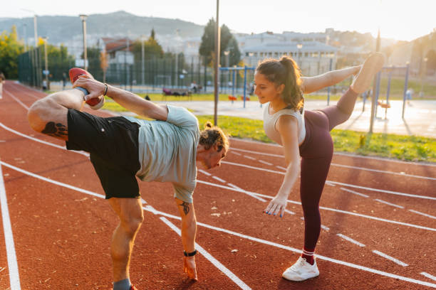 istock Young man and young woman stretching while exercise at the stadium 2187206013