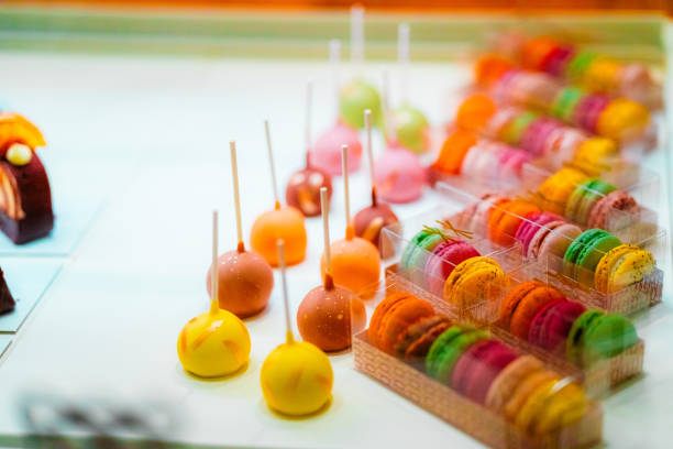 An enticing array of colorful cake pops and macarons displayed in a bakery. A vibrant showcase of sweet treats, evoking delight and indulgence.