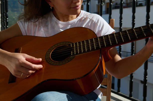 istock Woman playing acoustic guitar on a sunny balcony 2187208208