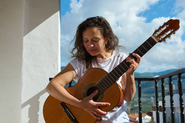 istock Woman playing guitar on sunny balcony with mountain views 2187208210