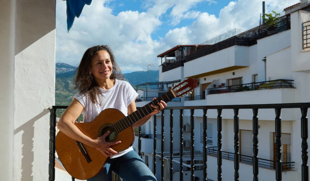 istock Woman enjoying playing guitar on a sunny balcony 2187208212