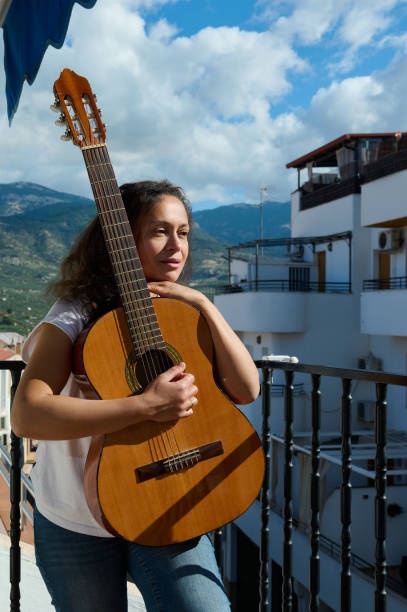 istock Woman with guitar enjoying a sunny day on a balcony 2187208215