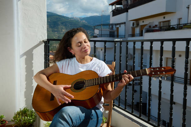 istock Woman enjoying playing guitar on a sunny balcony afternoon 2187208241