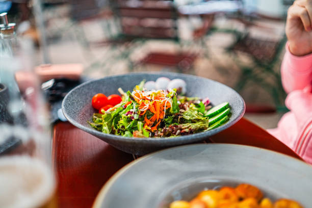 istock Fresh Vibrant Salad Bowl with Cherry Tomatoes, Cucumber Slices, and Mixed Greens in a Rustic Cafe Setting 2187210184