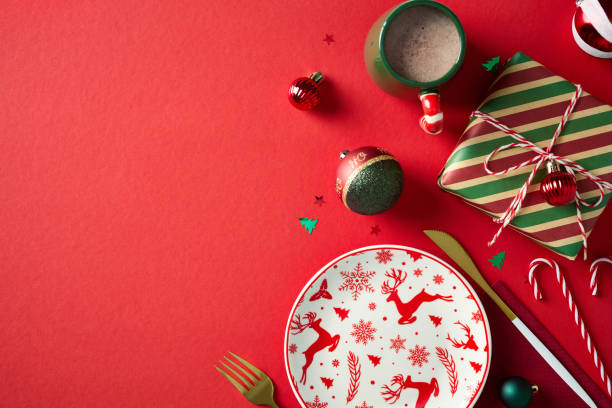 istock Christmas table top view with festive empty plate, cutlery, vintage gift box, cacao cup, Xmas decorations on red background. 2187210464