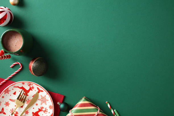 istock Festive holiday table setting with Christmas decorations. Features reindeer plate, red napkin, candy cane, and hot cocoa on a green background 2187210895
