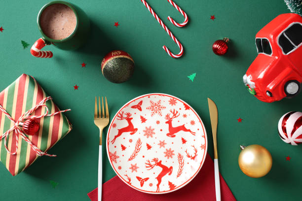 istock Christmas table setting with empty plate, golden cutlery, candy canes, vintage gift box, festive ornaments on green background. Flat lay, top view. 2187210986