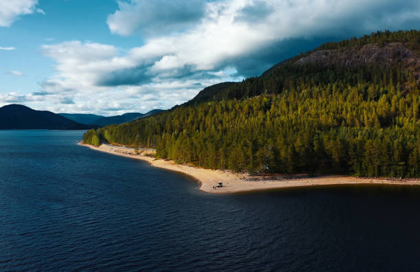 A tranquil lake scene showcasing a forested shoreline under a cloudy sky, perfect for nature lovers.