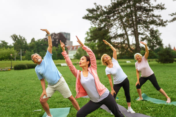 istock Senior Group Yoga Session with Instructor in Park 2187215490