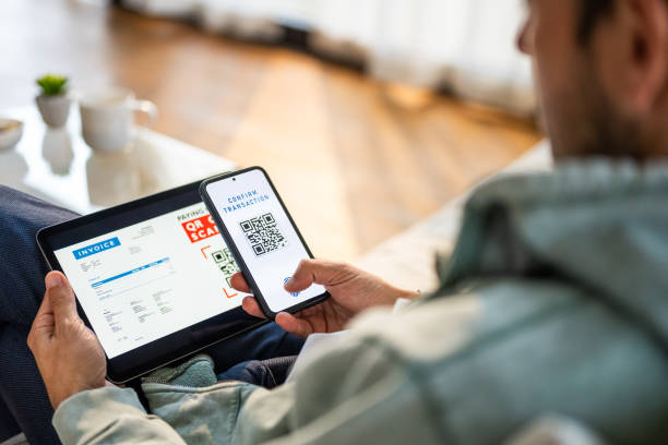 istock Mid Adult Man Completes Online Purchase with QR Code Scan at Home 2187216612