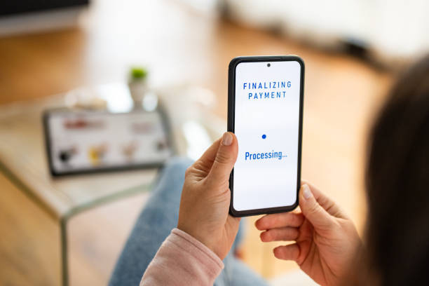 istock Mid Adult Woman Completes Payment Using Smartphone at Home 2187216618