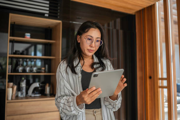 istock Concerned Asian Woman Using Tablet in Indoor Setting 2187217276