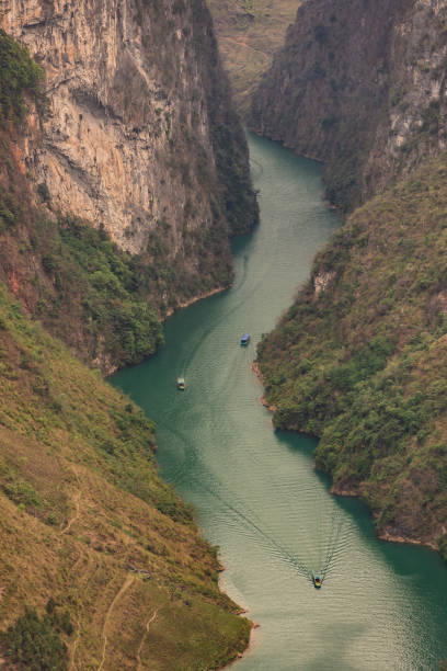This captivating photograph showcases the dramatic landscape of Tu San Gorge in Ha Giang, Vietnam, with the Nho Que River winding its way through the steep, towering cliffs